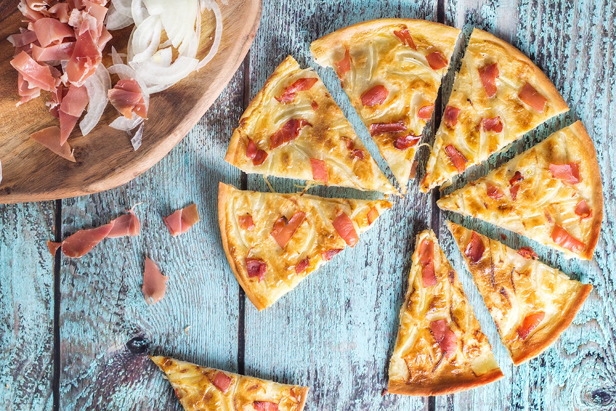 Tarte Flambee or Flammkuchen is a savory Alsatian pizza, topped with delicious sauce, onion and bacon! | cookingtheglobe.com