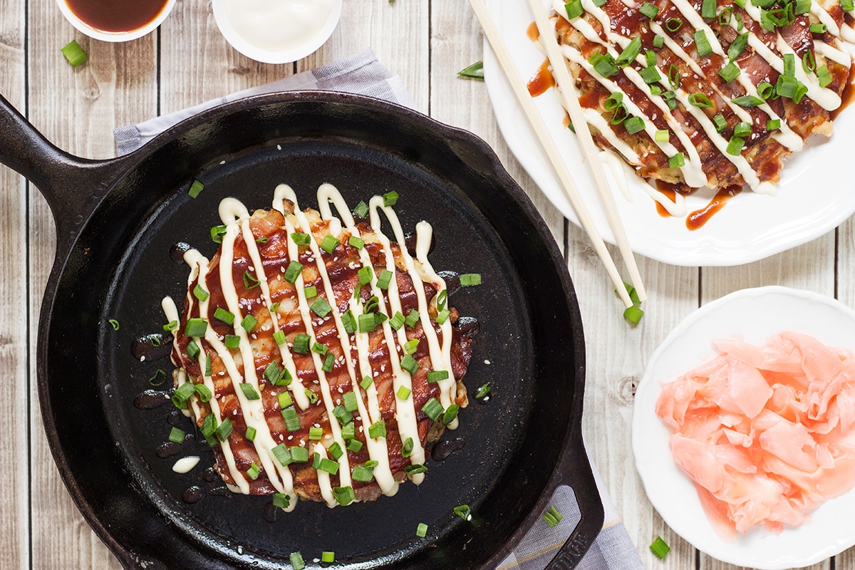 This traditional Japanese pancake (Okonomiyaki) is filled with cabbage and topped with sliced pork and amazing sauce! | cookingtheglobe.com
