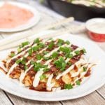 These traditional Japanese pancakes (Okonomiyaki) are filled with cabbage and topped with sliced pork and amazing sauce! | cookingtheglobe.com