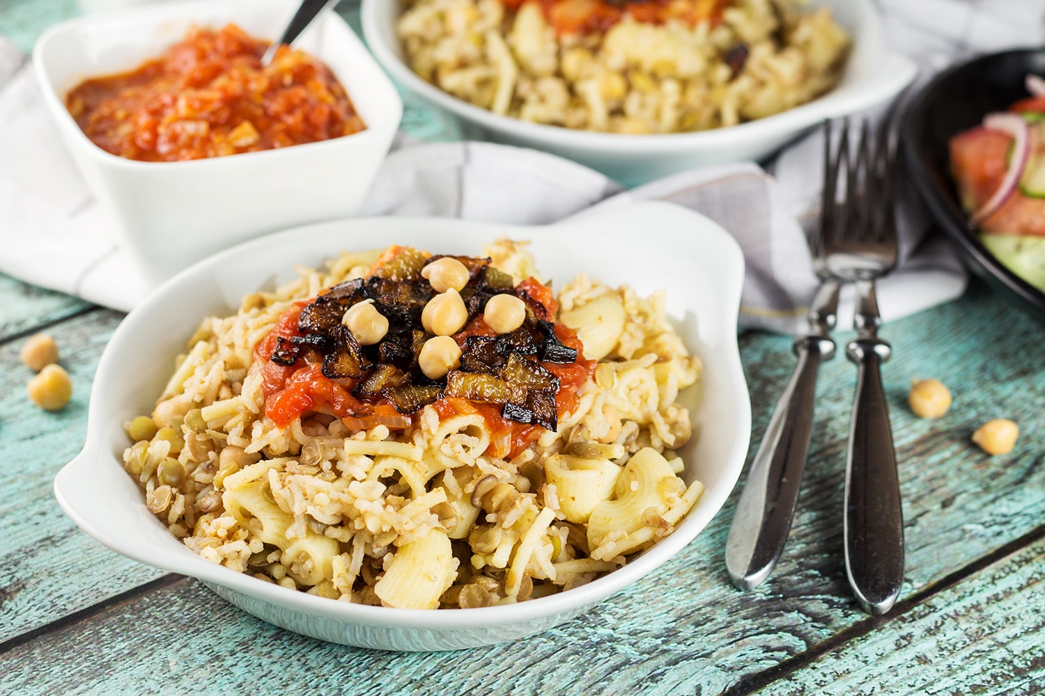 Koshari, or lentils and rice, is a national Egyptian dish. It also features pasta, chickpeas, fried onions, and a homemade tomato sauce. Healthy, filling, nutritious! #vegetarian #vegan| cookingtheglobe.com