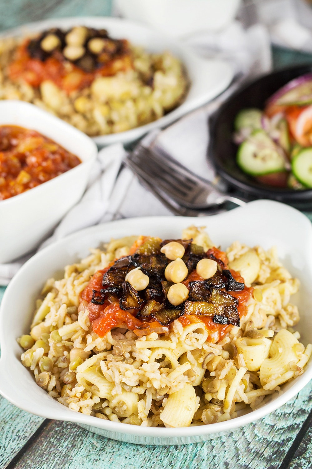 Koshari, or lentils and rice, is a national Egyptian dish. It also features pasta, chickpeas, fried onions, and a homemade tomato sauce. Healthy, filling, nutritious! #vegetarian #vegan| cookingtheglobe.com