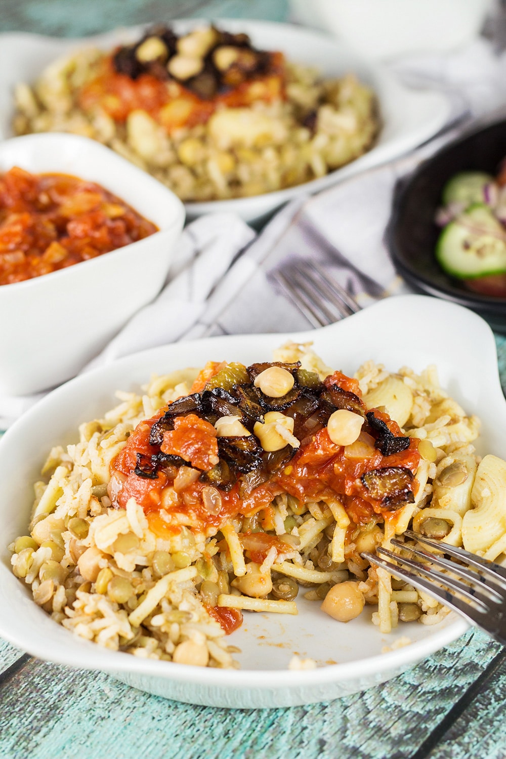 Koshari, or lentils and rice, is a national Egyptian dish. It also features pasta, chickpeas, fried onions, and a homemade tomato sauce. Healthy, filling, nutritious! #vegetarian #vegan| cookingtheglobe.com