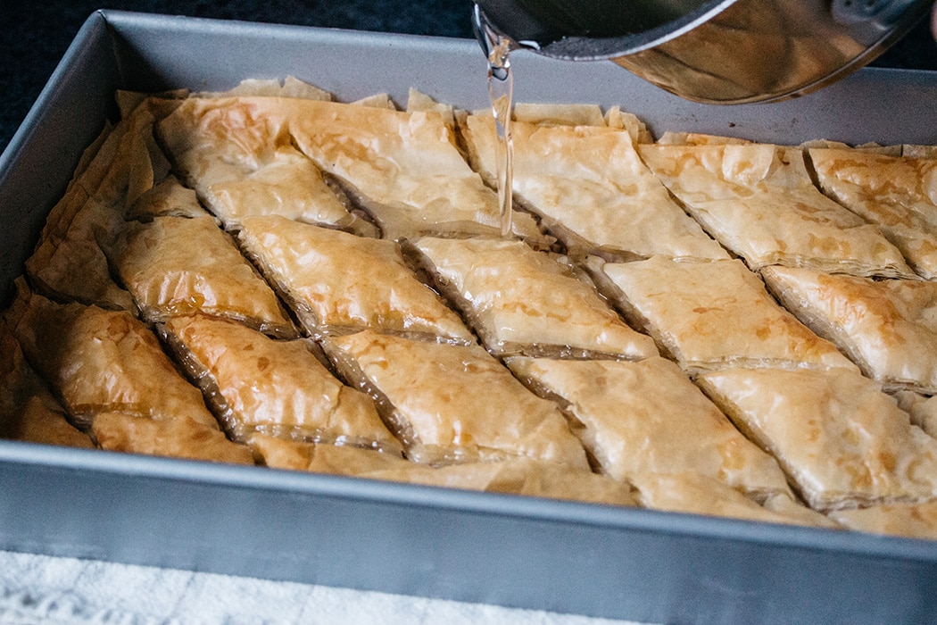 Pouring sugary syrup over Turkish baklava
