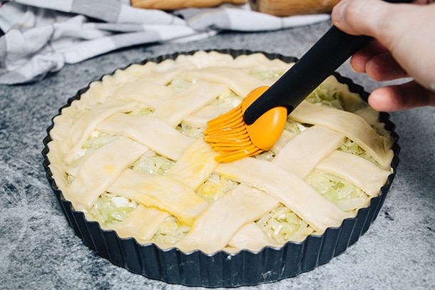 Brushing cabbage pie dough strips with egg yolk