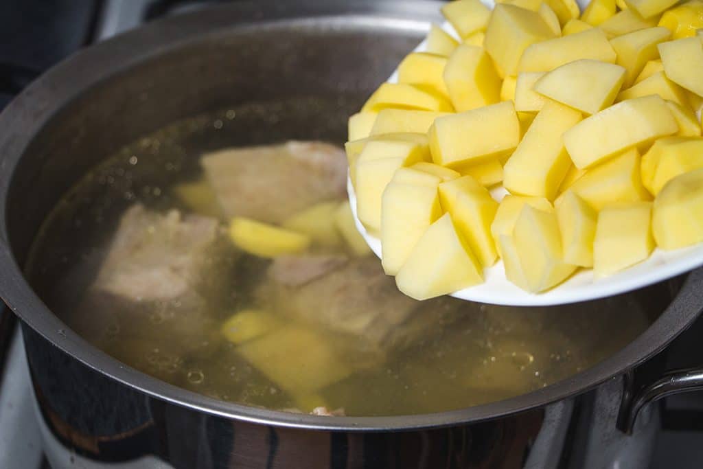 Adding chopped potatoes to the soup