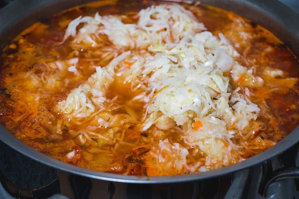 Adding sauerkraut to the soup