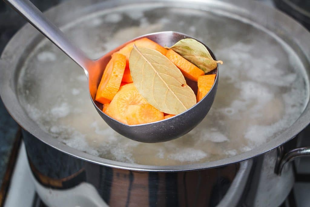 Adding carrots and bay leaves to the beef stock