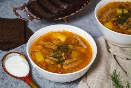 Russian sour cabbage soup served with sour cream and black bread