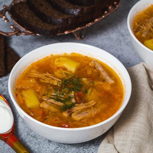 Russian sour cabbage soup served with sour cream and black bread