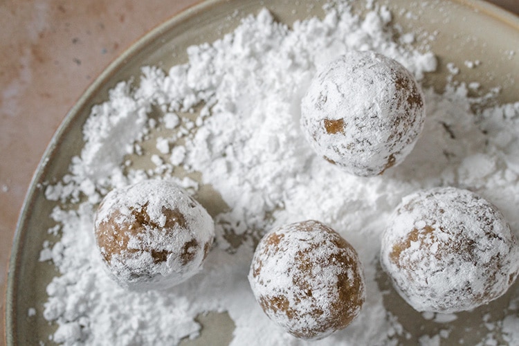 Rolling Moroccan walnut cookies in powdered sugar