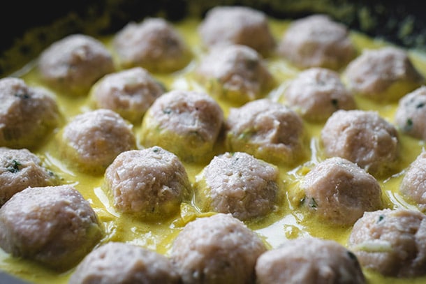 Chicken meatballs cooking in a creamy korma sauce