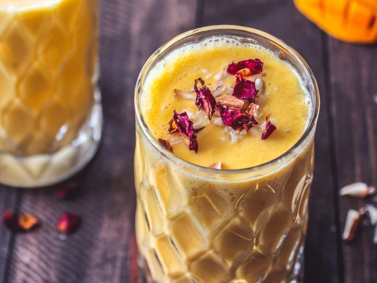 Mango lassi in tall glass on wooden table