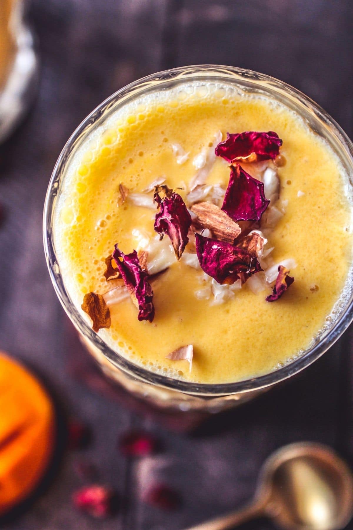 Overhead picture of glass of lassi with almonds and rose petals