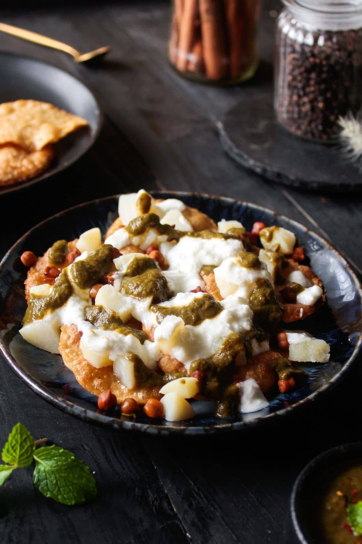 Papdi chaat on black bowl topped with mint chutney