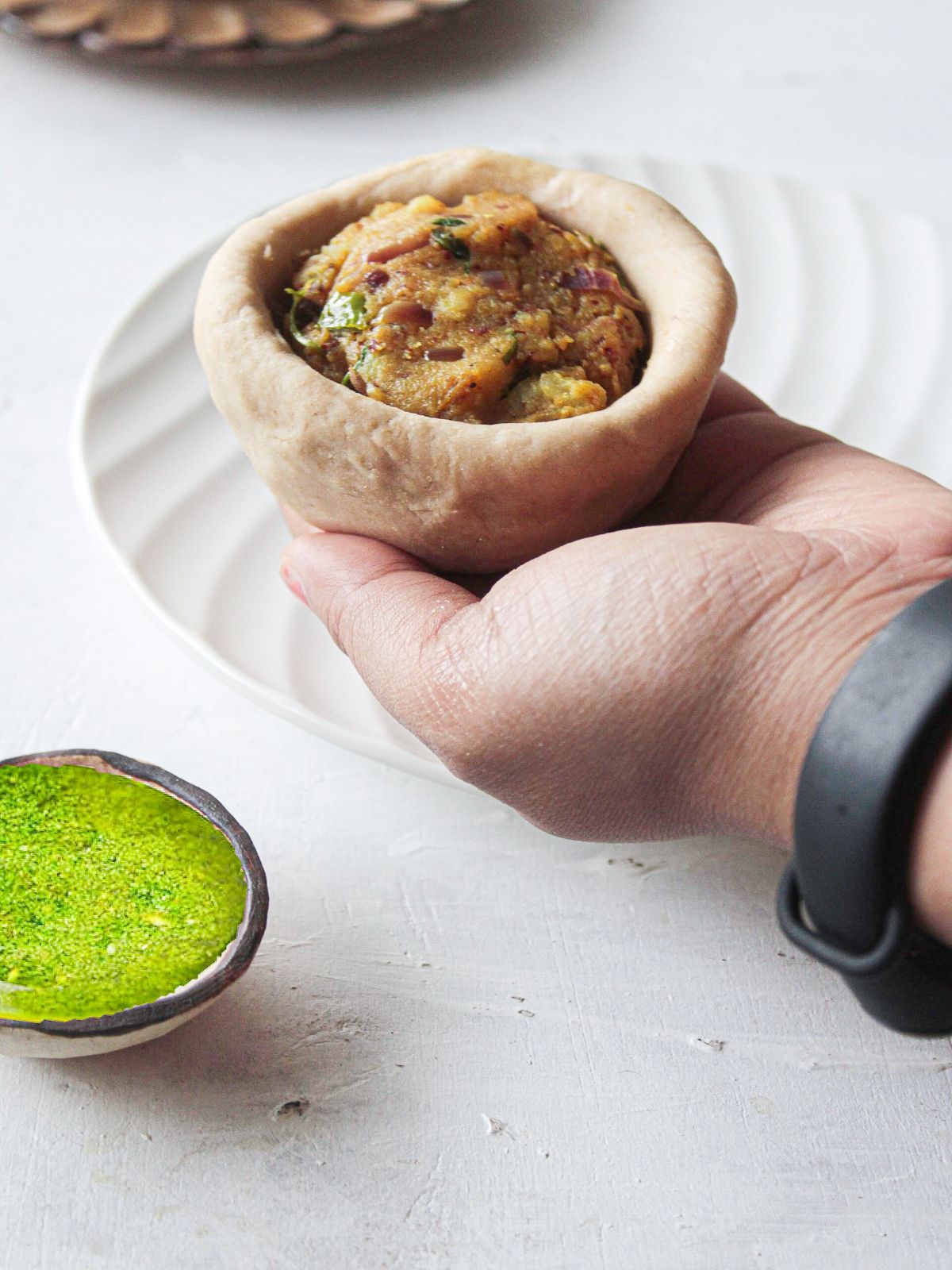Hand holding dough bowl filled with potatoes and spices