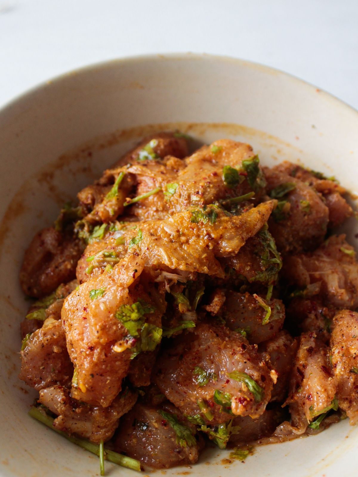 Chicken breasts coated in spices and coriander in large white bowl