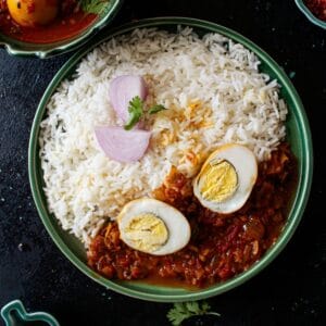 Bright green bowl filled with rice and egg curry with egg cut in half