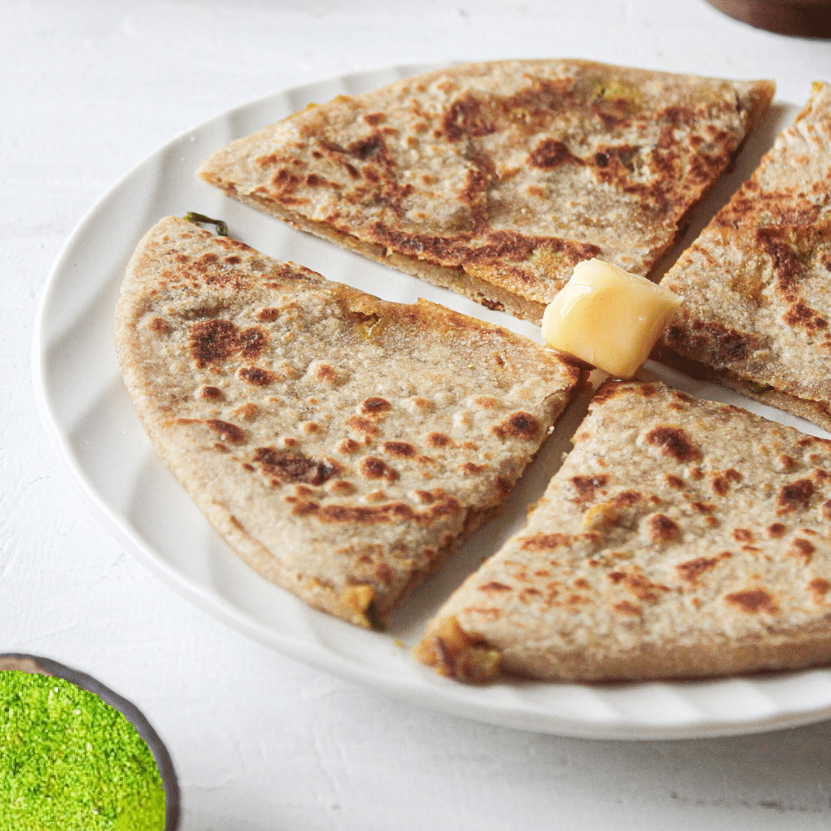 Sliced aloo paratha on white plate