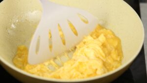 White spatula in skillet with scrambled eggs