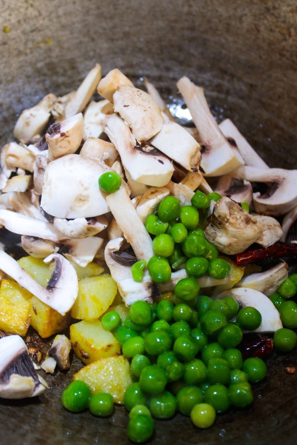Mushrooms peas and potatoes in a skillet