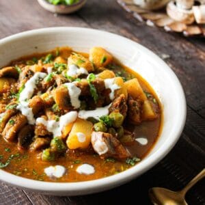 White bowl filled with potato and mushroom curry