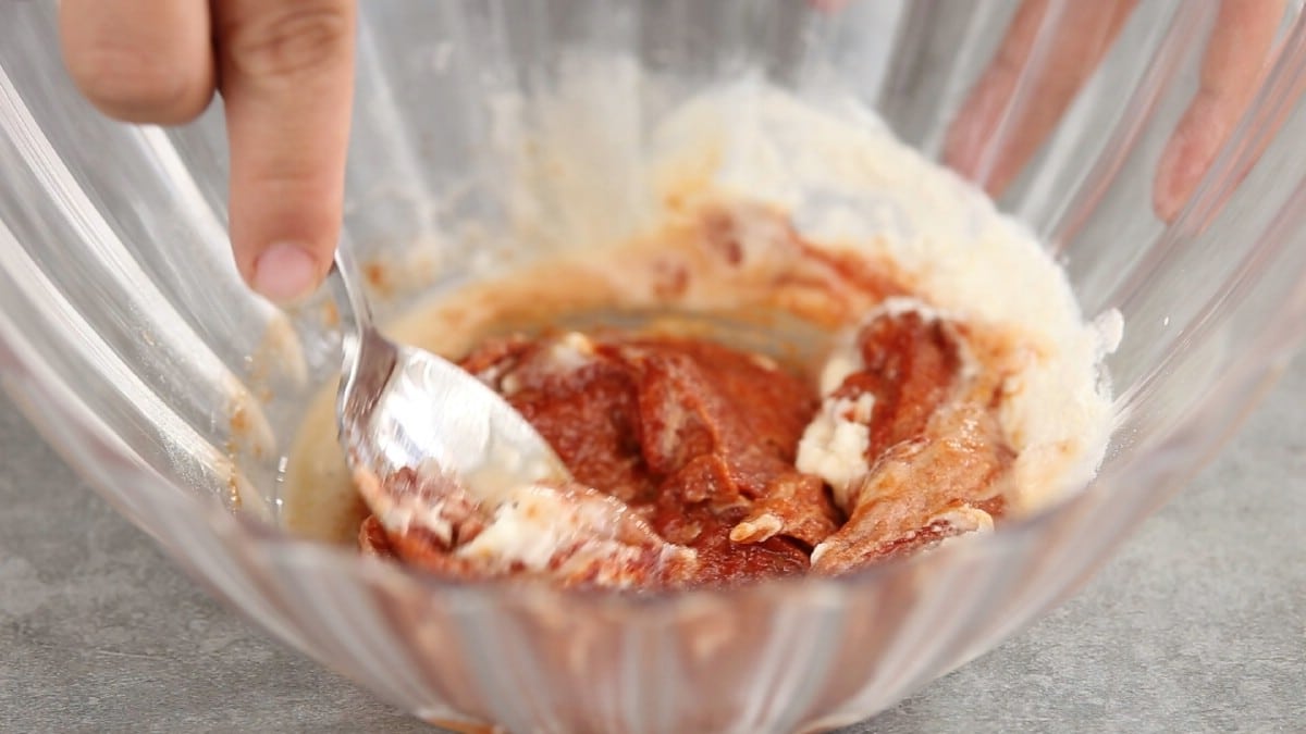 Spoon in bowl with tomato sauce and flour