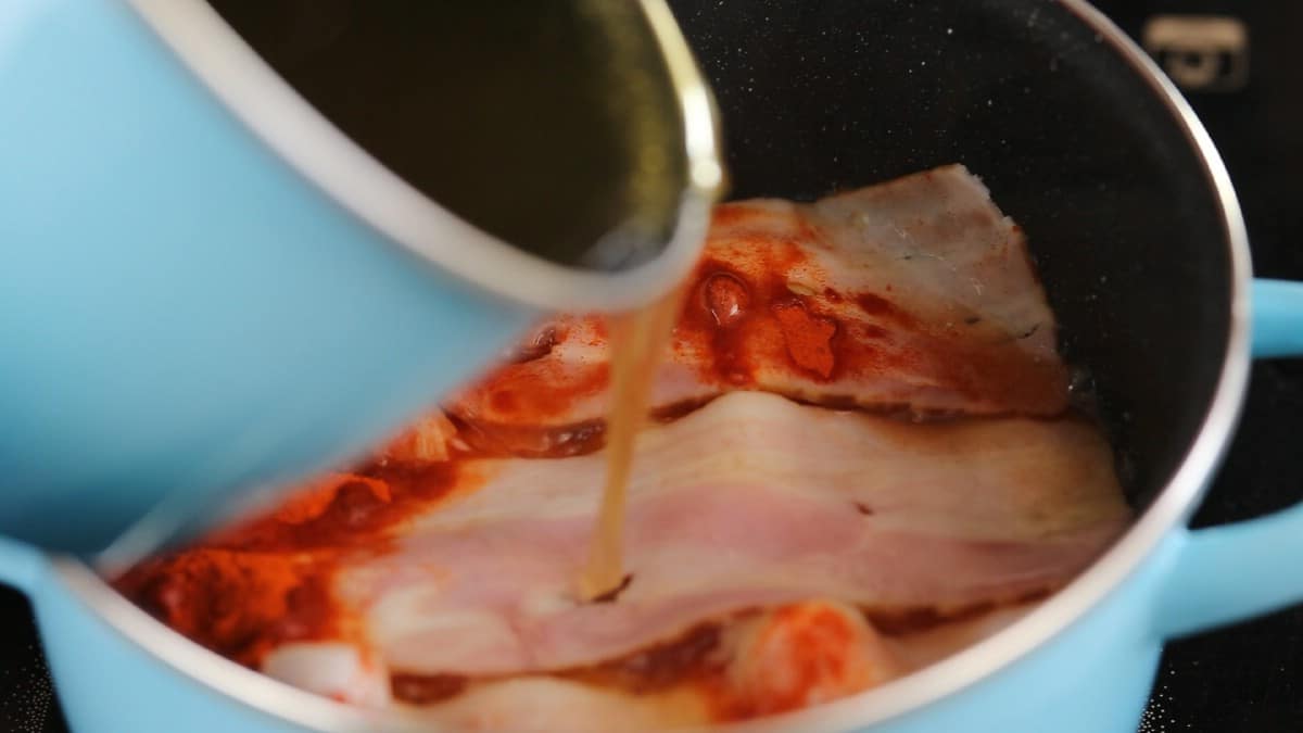 Teal pan pouring broth over bacon