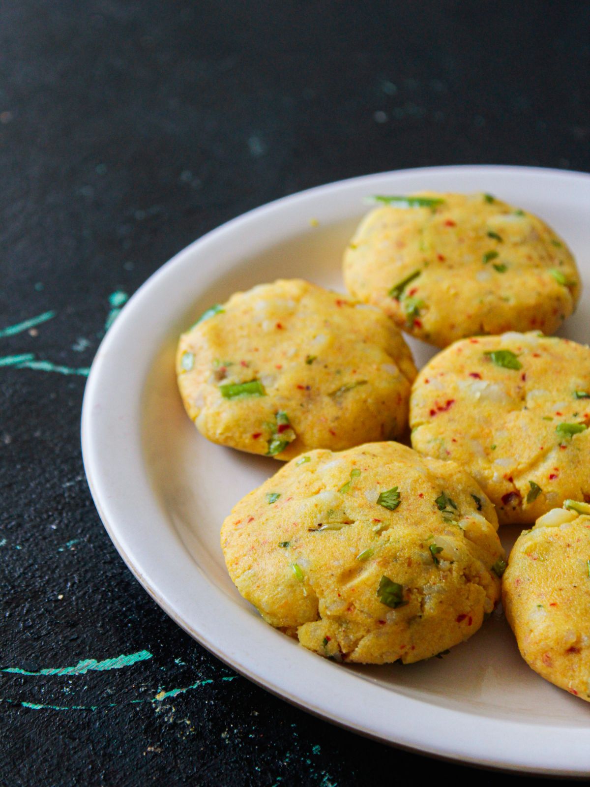 White plate of potato patties sitting on a black table