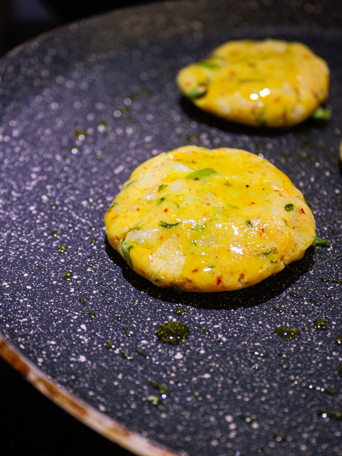 Potato patties in oiled skillet with oil over top