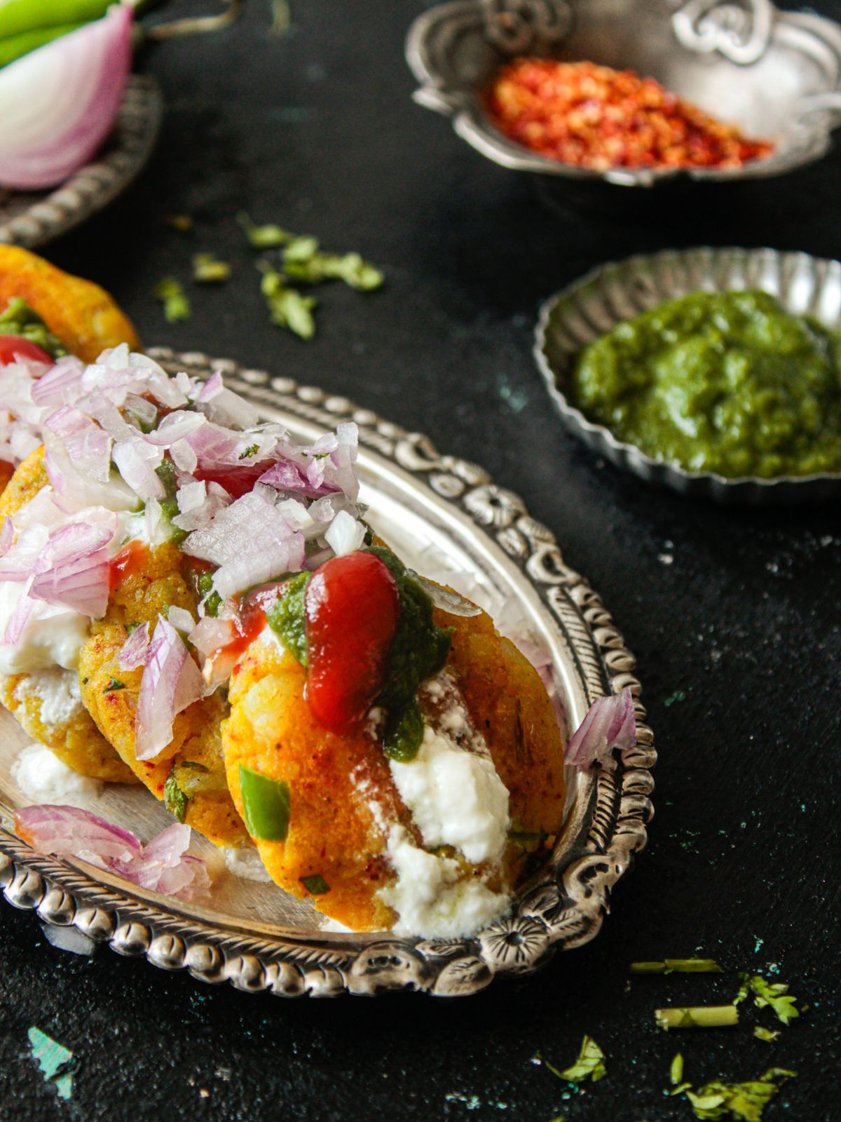 Platter of potato patties topped with chutney yogurt and onions