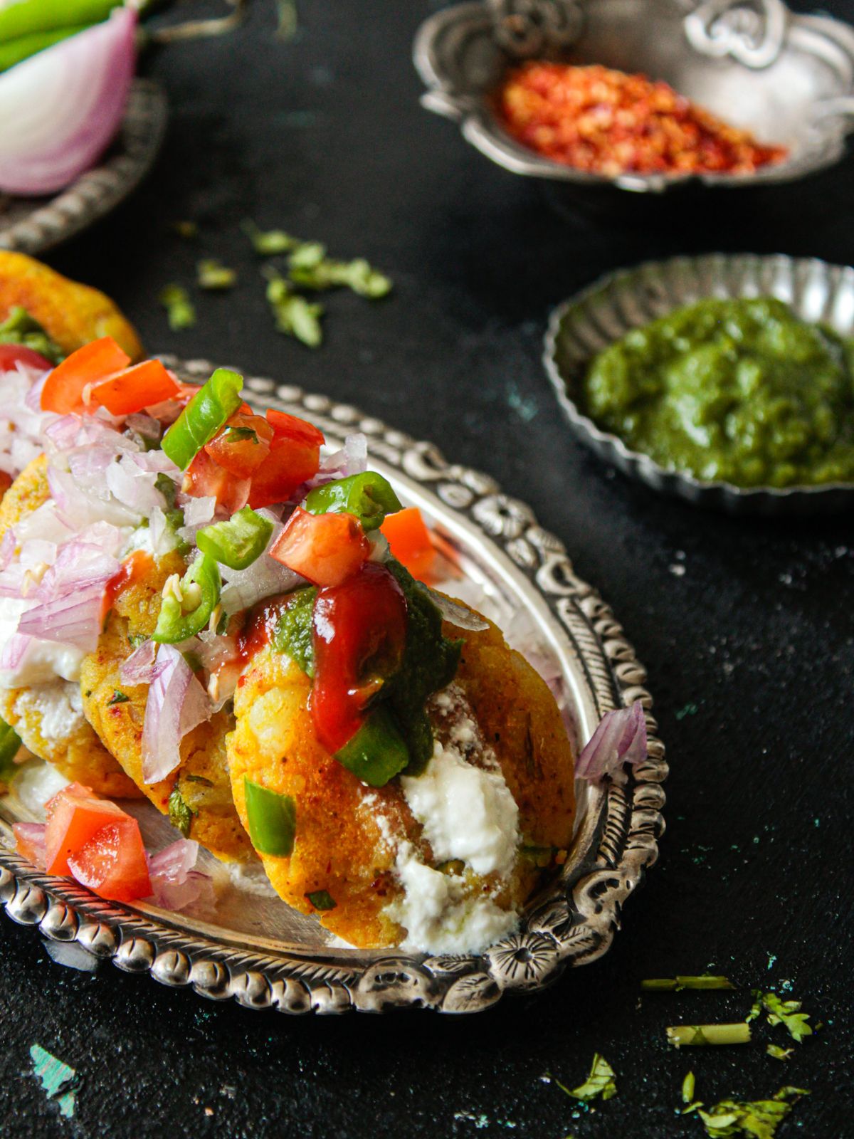 Indian potato patties on silver plate with chaat on top