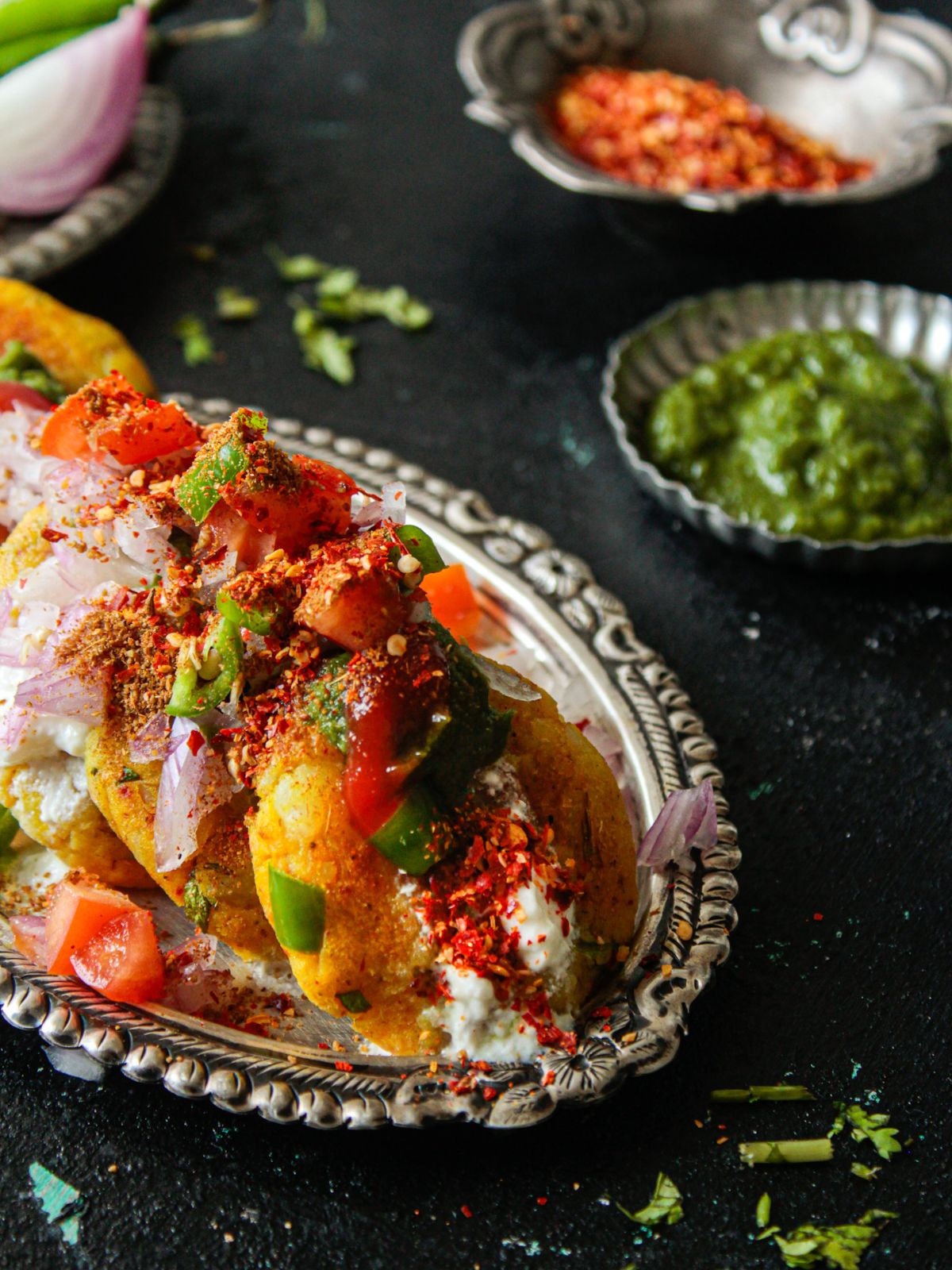 Aloo tikki topped with yogurt chutney and chili flakes