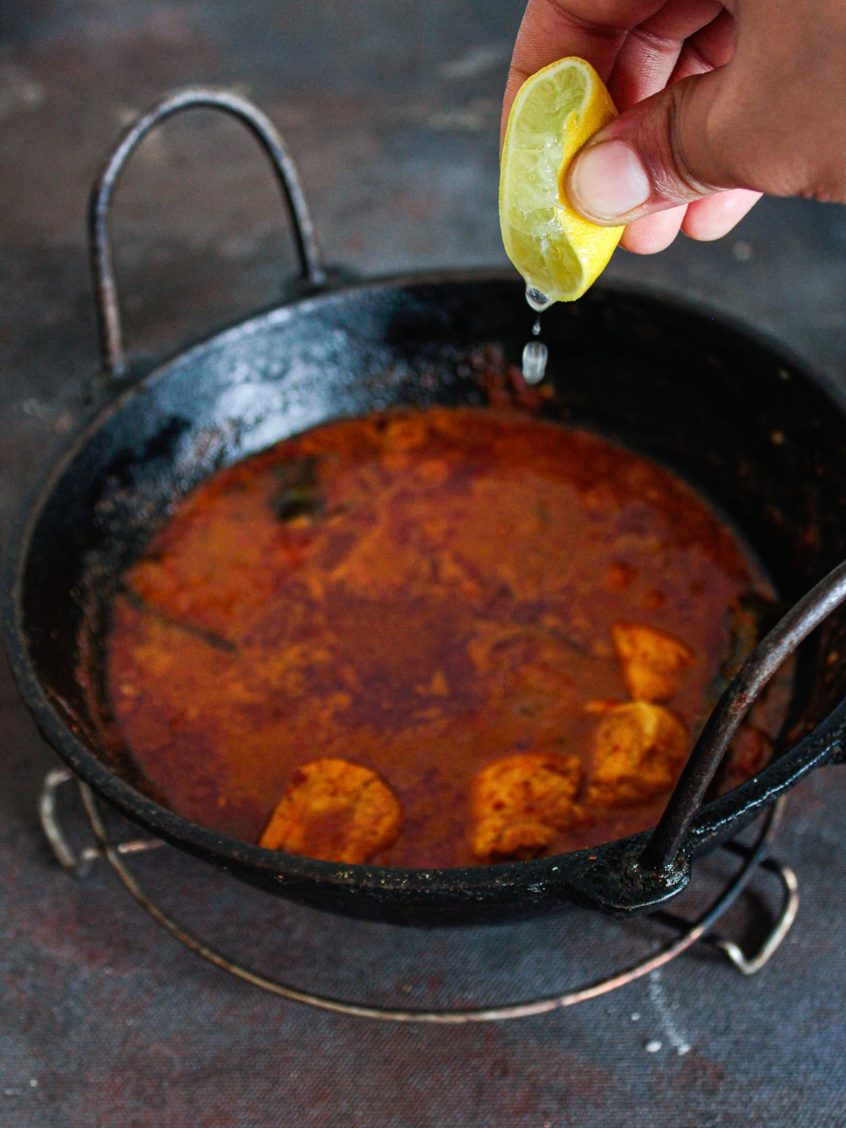 hand squeezing lemon into curry