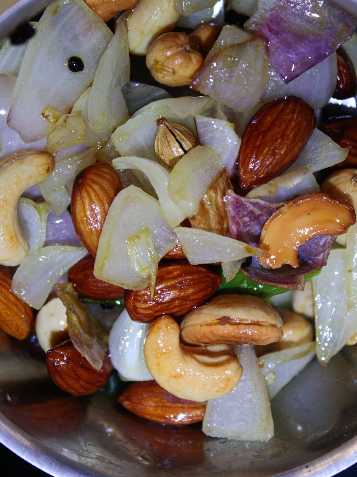 Cooked onions and cashews in skillet