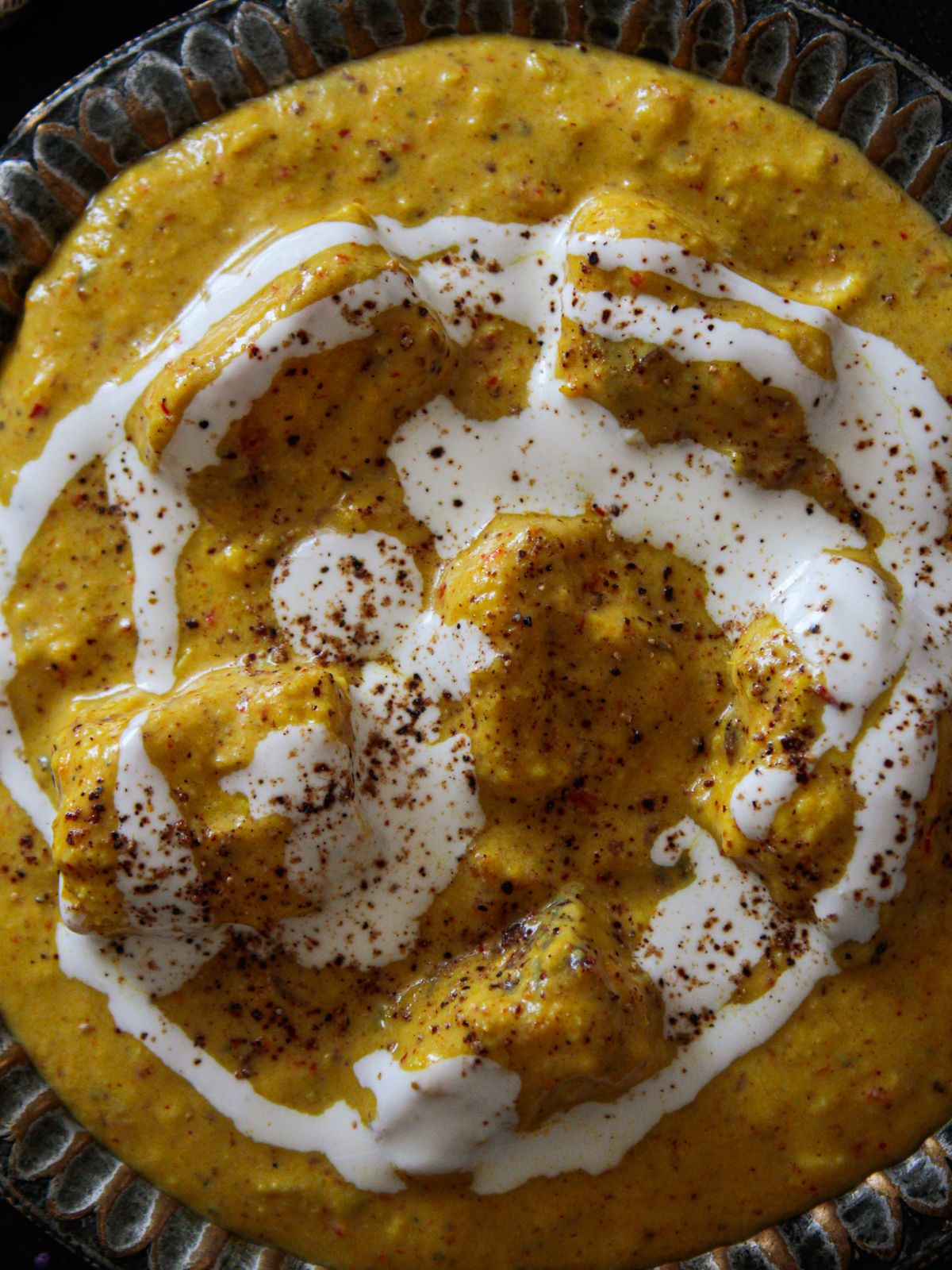 Indian Shahi Paneer with cream on top in large bowl