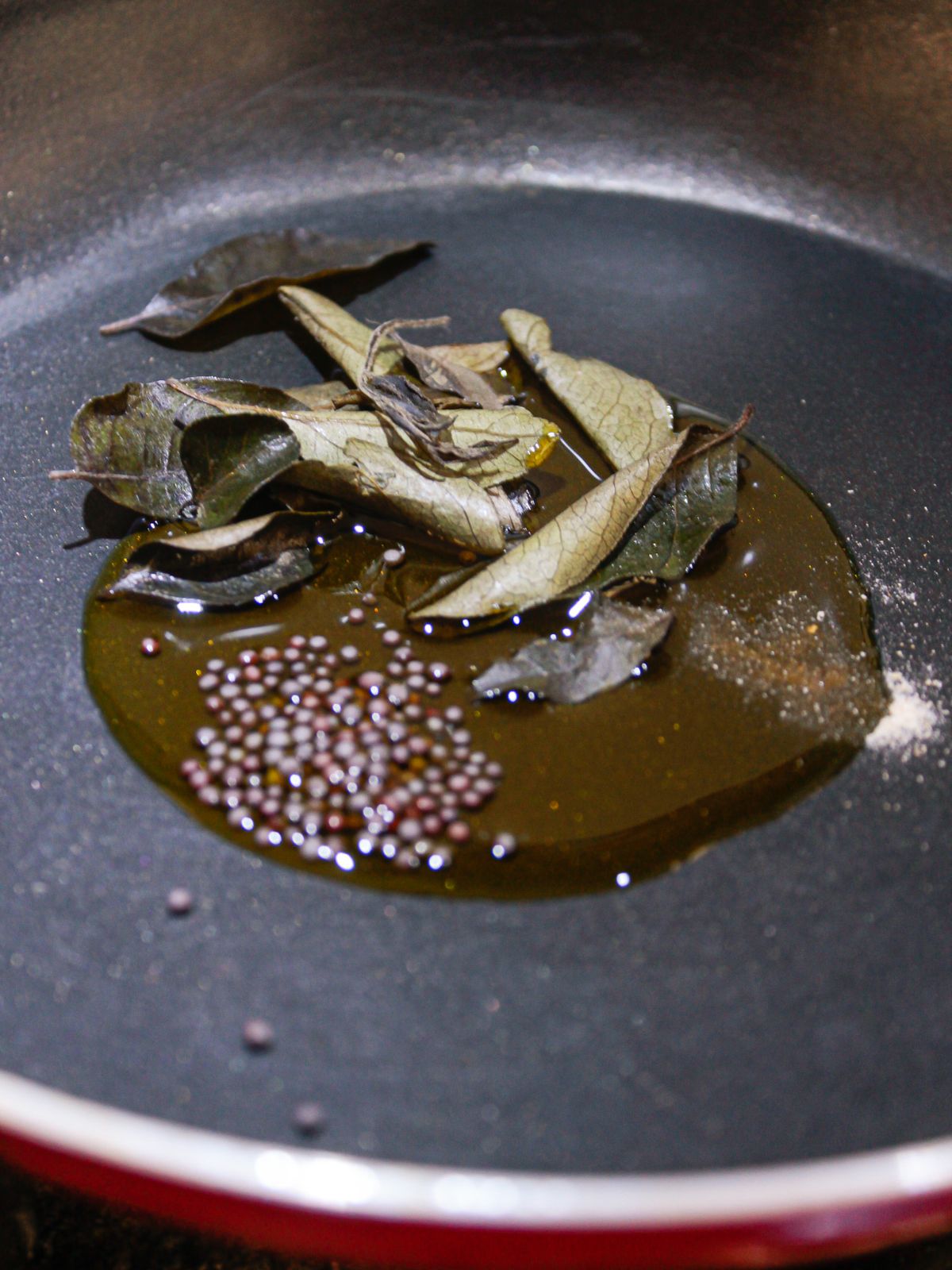 mustard seeds and curry leaves in oil in skillet