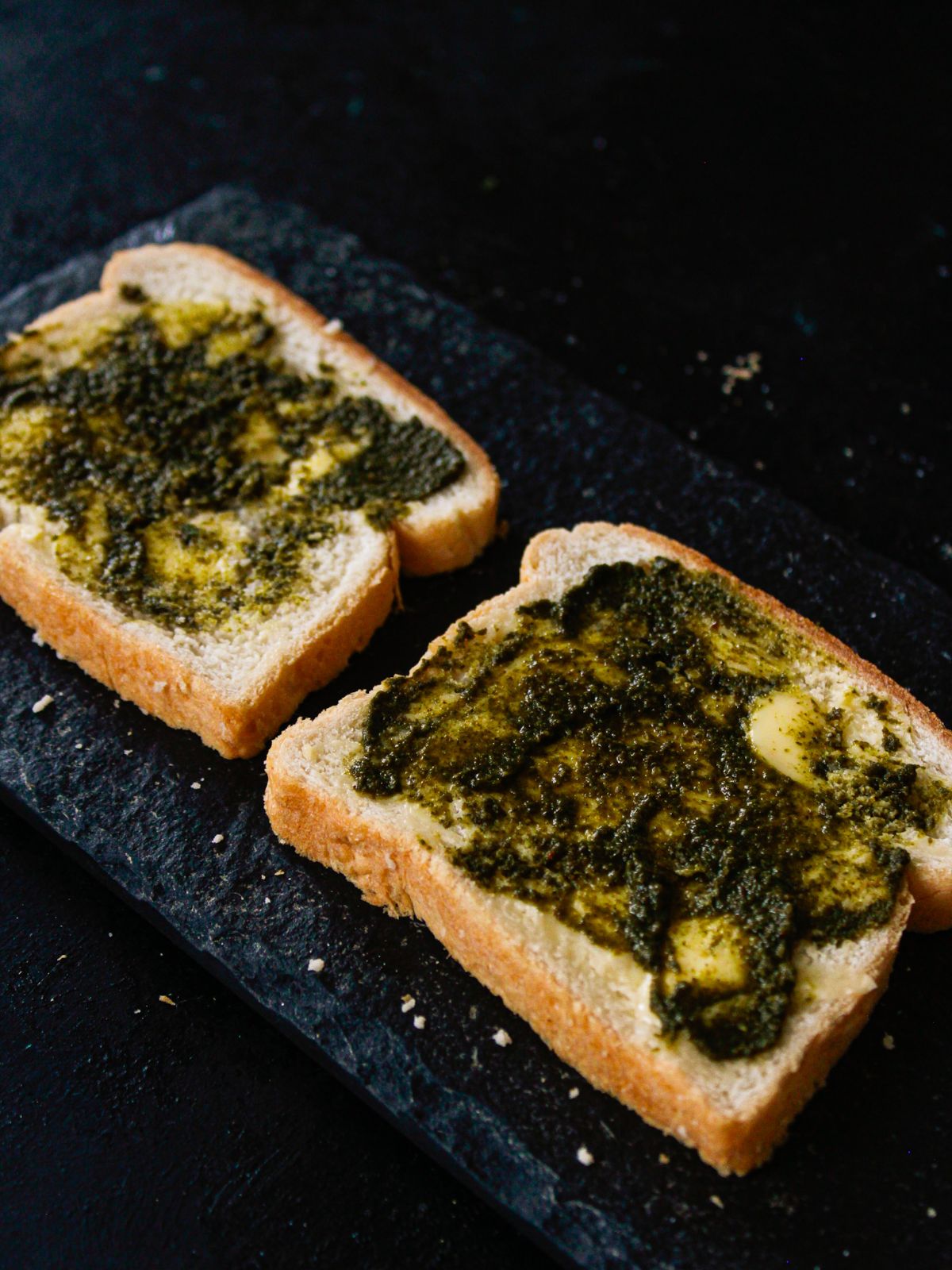 green chutney spread on top of two slices of bread on black table