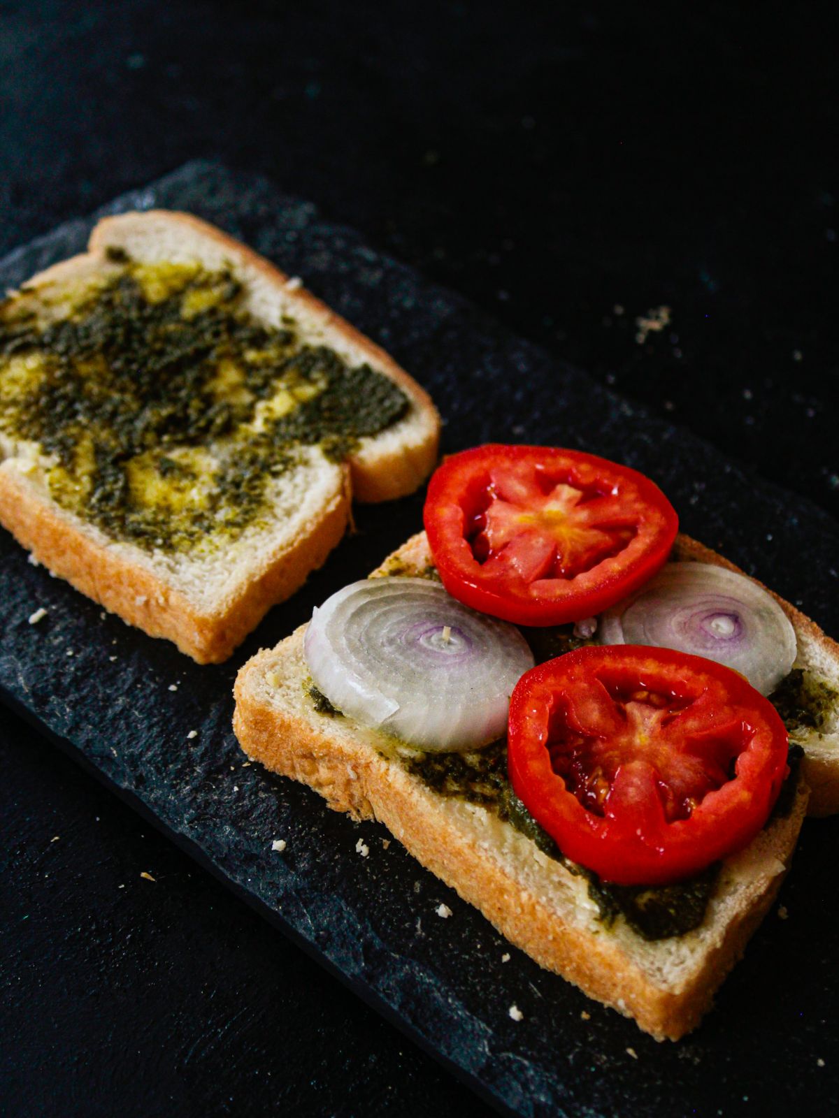 two slices of bread topped with green chutney and vegetables on table