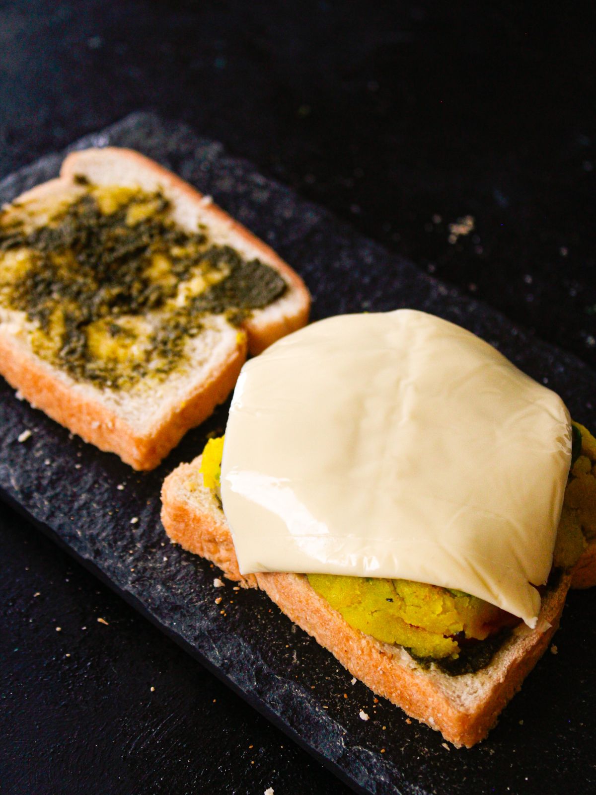 bread with green chutney on one side with stuffed bread covered in cheese opposite