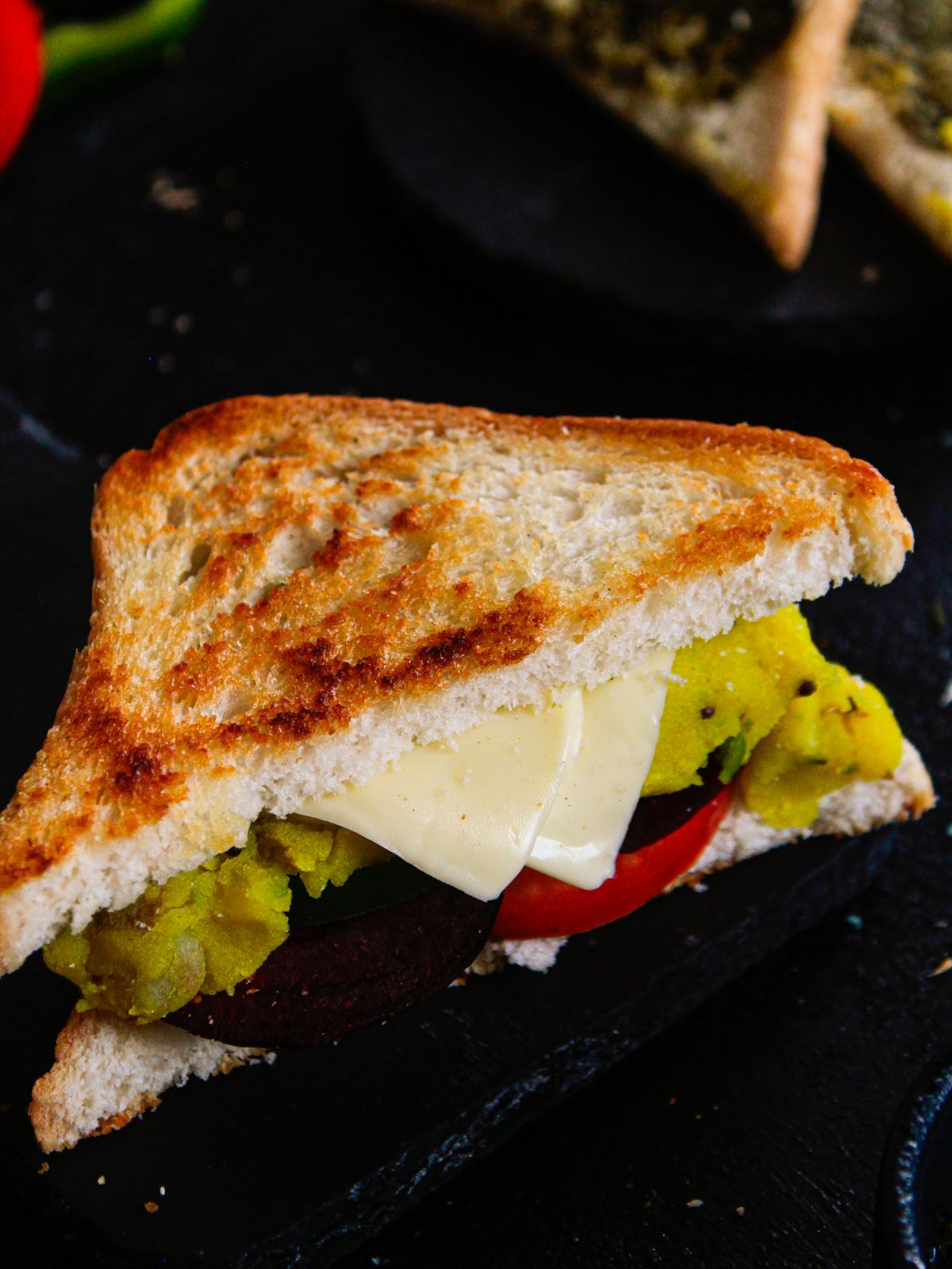 sandwich with cheese and vegetables on black table