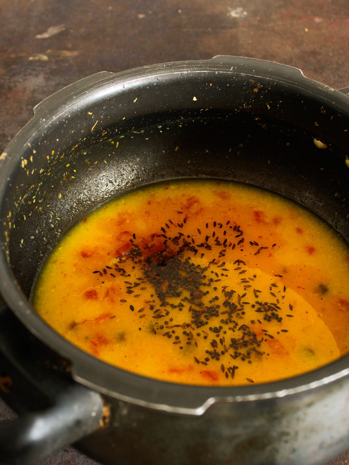 Saucepan of bonda soup topped with seeds
