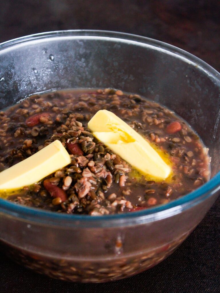 glass bowl of cooked lentils and kidney beans with butter on top
