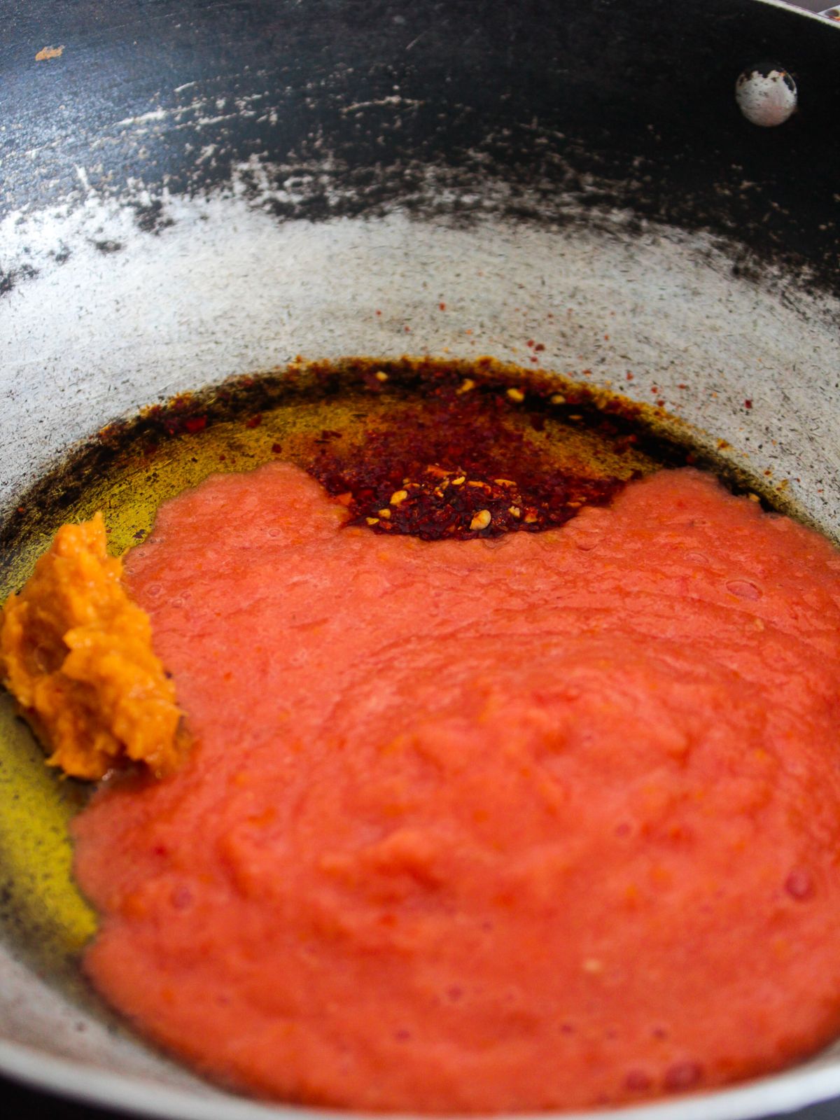 tomato puree in skillet with red pepper flakes
