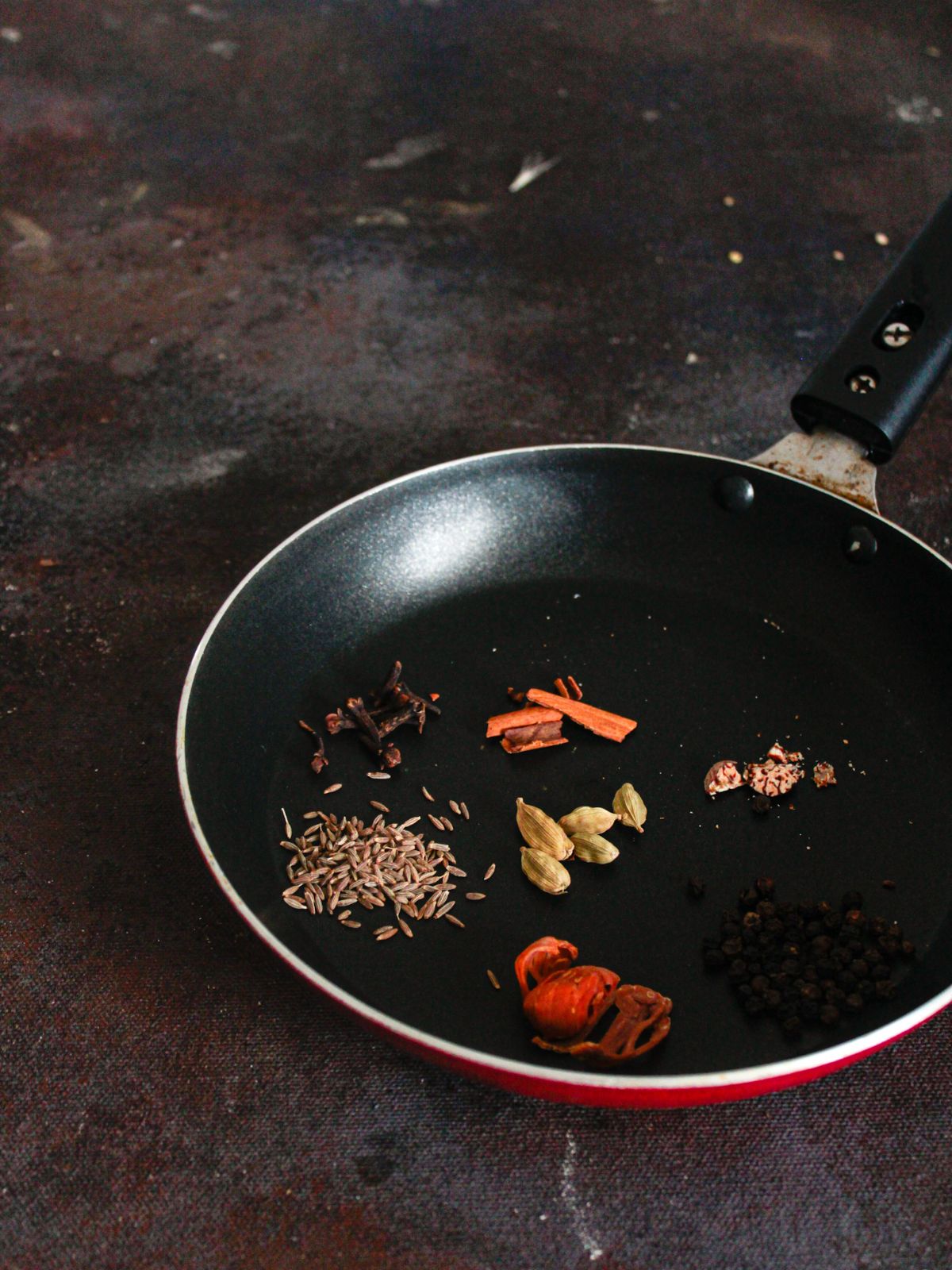 small skillet with whole seeds and cloves