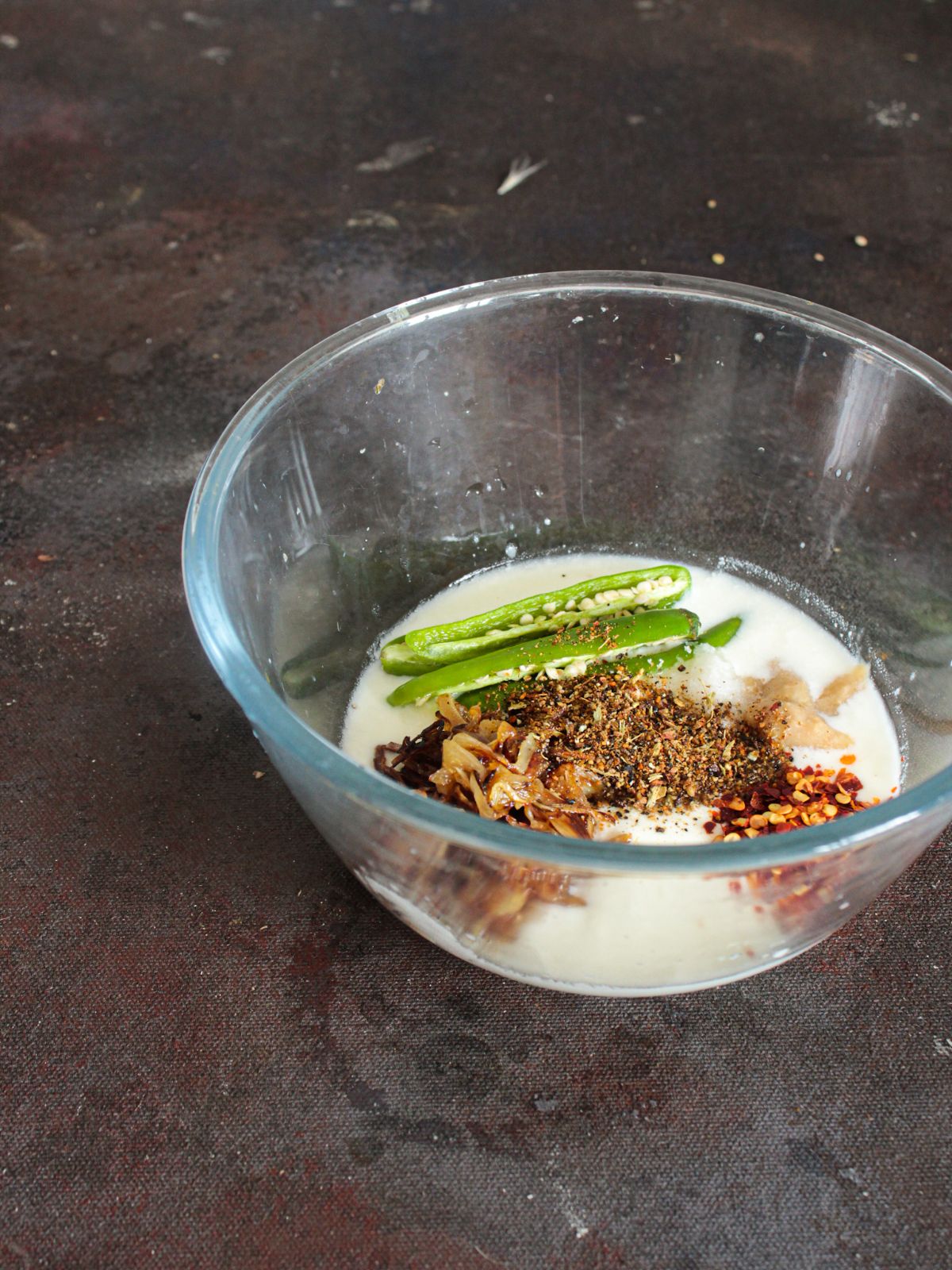 herbs and spices on top of yogurt in glass bowl