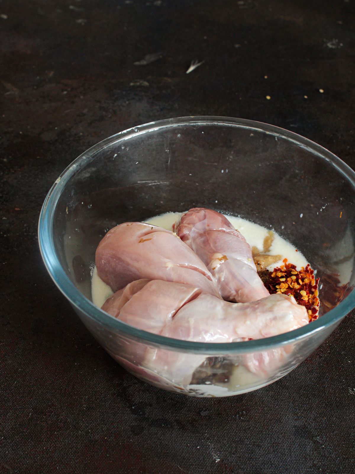 raw chicken on top of yogurt in bowl