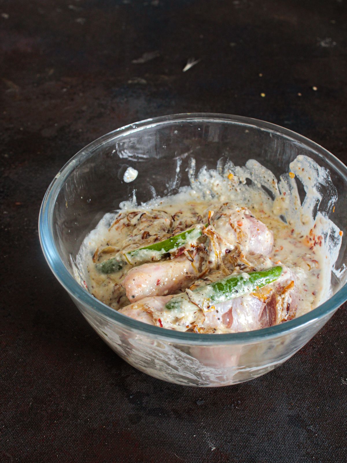 glass bowl of yogurt marinade with chicken legs