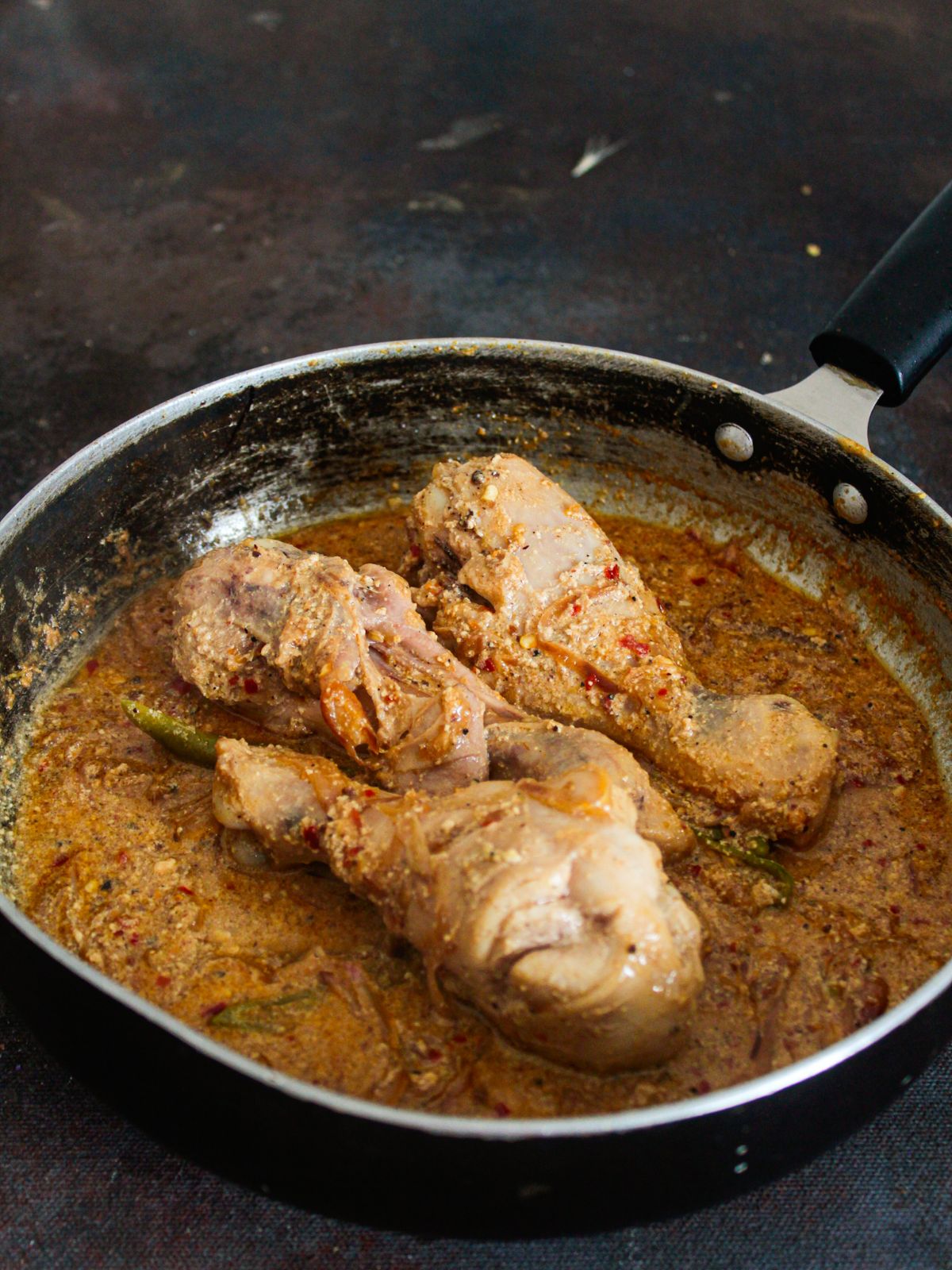 skillet with cooked chicken legs in sauce