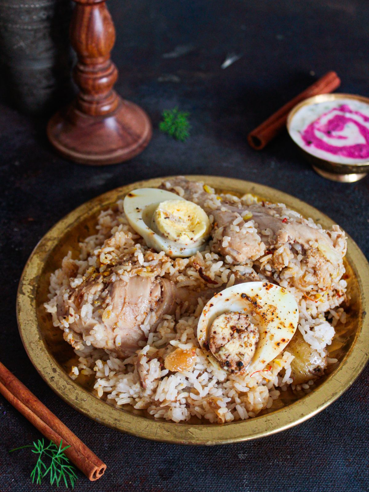 large bowl of biryani on black table by bowl of raita