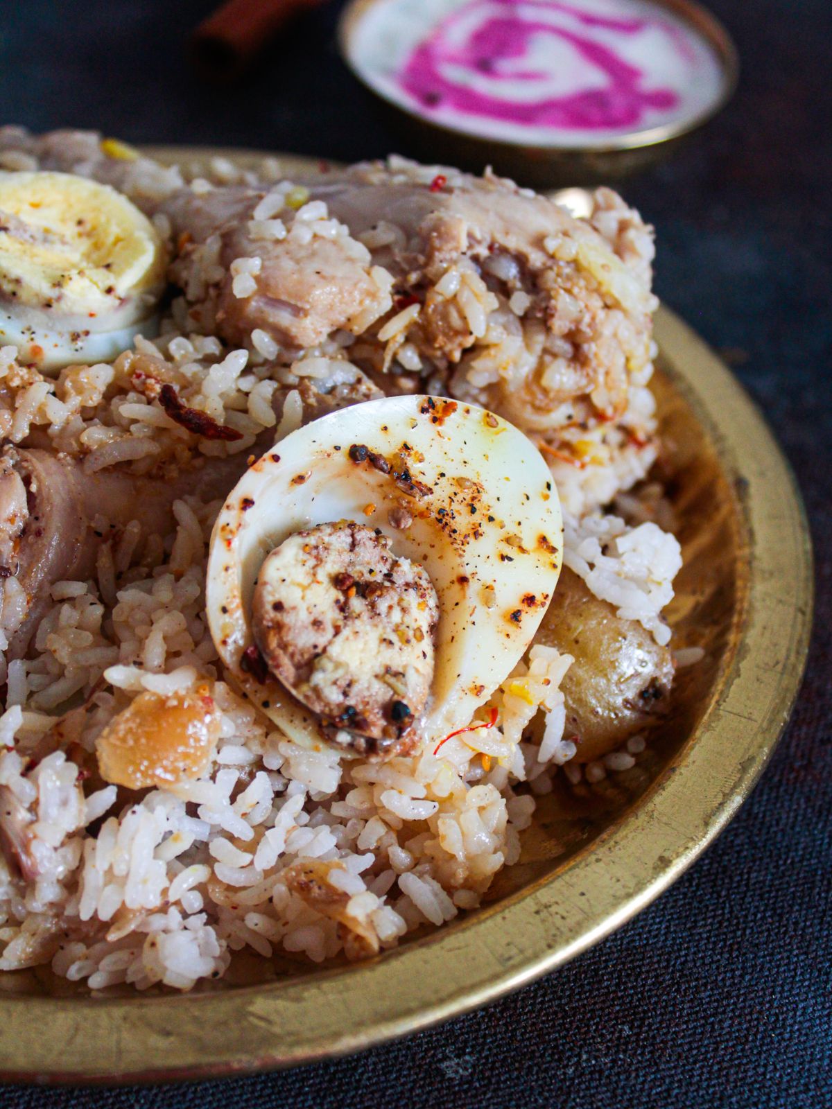 Gold bowl of chicken biryani on black table